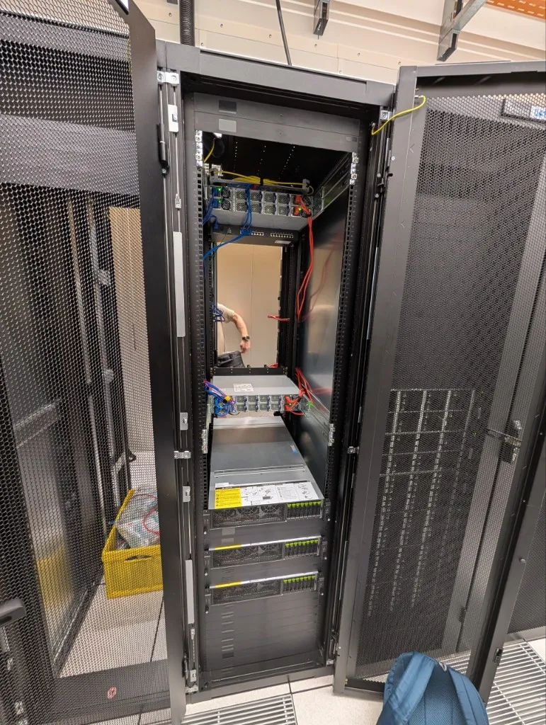 An open server cabinet with stacked servers and structured cabling.